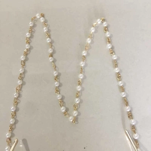 Macro view of gold chain with white pearls and cylindrical metal end fastener