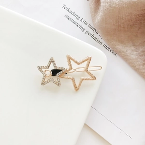 Detail of star-shaped gold alloy hair clip with matte finish and white rhinestones