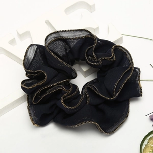 Detail of dark blue fabric hair scrunchie with elegant golden edge stitching on white background