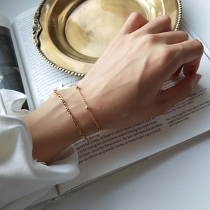 Detail of layered S925 silver golden bead bracelets worn for an elegant minimalist style
