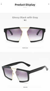 Detail view of glossy black oversized sunglasses with gradient grey lenses and gold accents