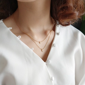 Close-up of golden double-layer necklace with star and moon charms on model neck