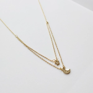 Close-up of double layer gold star and moon necklace with shimmering cubic zirconia