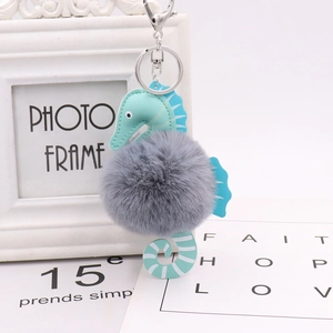 Cute seahorse keychain with blue-green PU leather and grey faux fur pom pom on white background