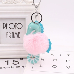 Detailed close-up of seahorse keychain with pink pom-pom and blue leather accents