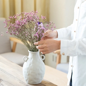 White ceramic textured vase with handles featuring pink and purple dried flowers