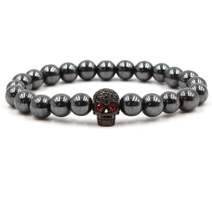 Gros plan sur bracelet en perles d'hématite avec tête de mort zircon aux yeux rouges