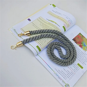 Close-up of grey braided rope shoulder strap with gold lobster clasps on a book