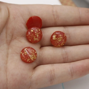 Macro detail of red oval resin cabochons with gold foil flakes for DIY jewelry
