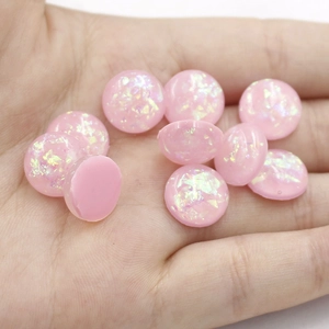 Detailed view of 12mm pink synthetic opal resin cabochons with iridescent foil in palm