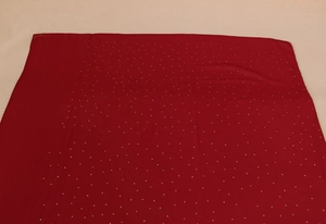 Vue détaillée d'une écharpe en mousseline rouge foncé avec motifs à pois dorés élégants