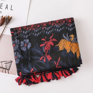 Detail of floral print scarf with vintage patterns and braided tassel edges on white background