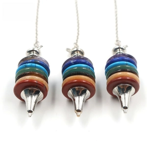 Close-up of three Seven Chakra stone pendulums with silver conical metal tips on white background