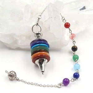 Detailed macro of chakra crystal stone pendulum with silver cone on white cluster
