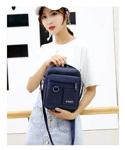 Detail of dark blue Oxford fabric bag showing adjustable shoulder strap and metal D-ring