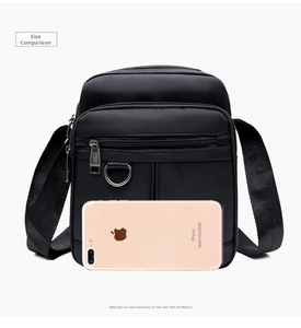 Close-up of black oxford crossbody bag with phone for size reference and scale