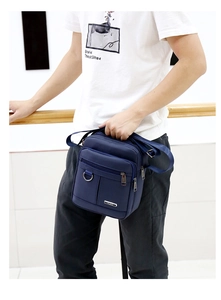 Detail view of a navy blue waterproof oxford fabric crossbody bag worn by a model