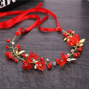 Detail of handmade bridal headband with red flowers, gold leaves, and crystal beads