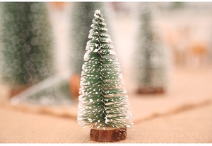 Macro shot of mini frosted pine needle Christmas tree with white snow and wooden base