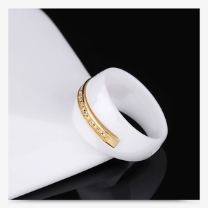 Macro shot of white ceramic ring featuring a gold band set with sparkling pavé crystals
