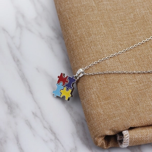 Macro shot of four-color puzzle pendant necklace on a marble surface