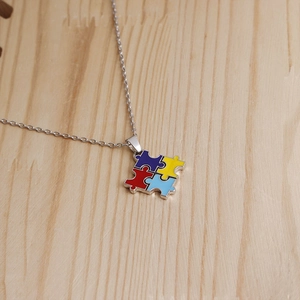 Close-up of four-piece colorful enamel puzzle necklace on light wood background