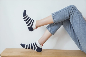 Detail of navy and white striped cotton socks with red heart heel tab worn on feet