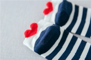 Macro shot of striped cotton ankle socks featuring a red heart embroidery detail