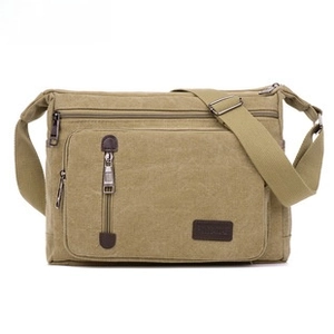 Detailed close-up of khaki canvas crossbody bag with multiple functional zipper pockets