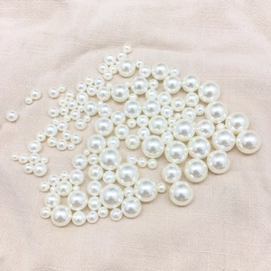 Close-up of high-quality iridescent white pearls in various sizes on linen fabric