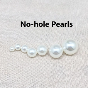 Detailed view of mixed size white non-perforated pearls with iridescent luster