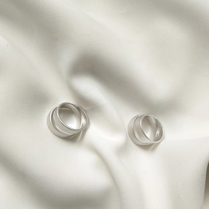 Close-up of S925 sterling silver rings with matte finish on elegant white silk fabric