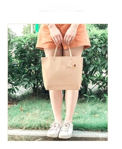 Close-up of kraft paper gift bag with sunflower charm in outdoor natural setting