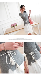 Detail of white braided waist belt with tassels on grey knit top and white layered skirt