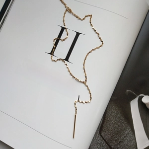 Detail of minimalist 925 silver gold-plated Y-shaped necklace with slim cylinder pendant