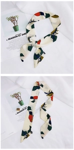 Detail of beige silk scarf with toucan and green leaf print styled in a bow tie
