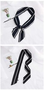 Close-up of black and white striped skinny silk scarf on French magazine backdrop