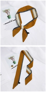 Detail of yellow silk scarf with black white stripes tied and laid on magazine
