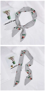 Detail of a black and white striped skinny scarf with floral embroidery on white fabric