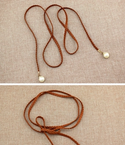 Detail of woven brown waist chain with elegant pearl pendant on linen background