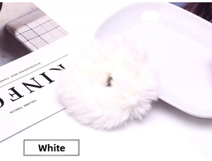 Close-up of soft white faux rabbit fur scrunchie on a minimalist white background