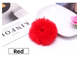 Detail view of a bright red fluffy faux rabbit fur scrunchie on a decorative tabletop