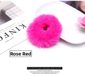 Close-up of fluffy rose red plush hair scrunchie on a decorative white ceramic tray