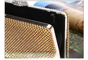 Detail showing the detachable chain design and sparkling rhinestones on the gold evening bag