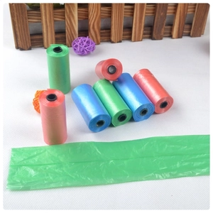 Detail view of multi-color biodegradable pet waste bag rolls on a white textured table