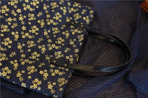 Détail du sac en toile bleu marine avec motifs dorés de fleurs de cerisier et vagues
