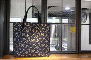Gros plan sur le sac en toile bleu marine aux motifs de cerisiers dorés et anse cuir