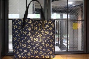 Détail du sac en toile bleu marine avec motifs sakura dorés et anses en cuir noir