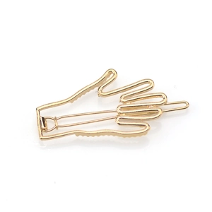 Gold palm hand hair clip in minimalist geometric style on white background