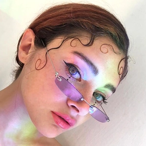 Close-up of model wearing purple cat eye sunglasses with silver metal frame and Y2K style